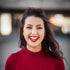 Smiling woman with long dark hair in a red top, representing Timeless Beauty products, confidence, and style.